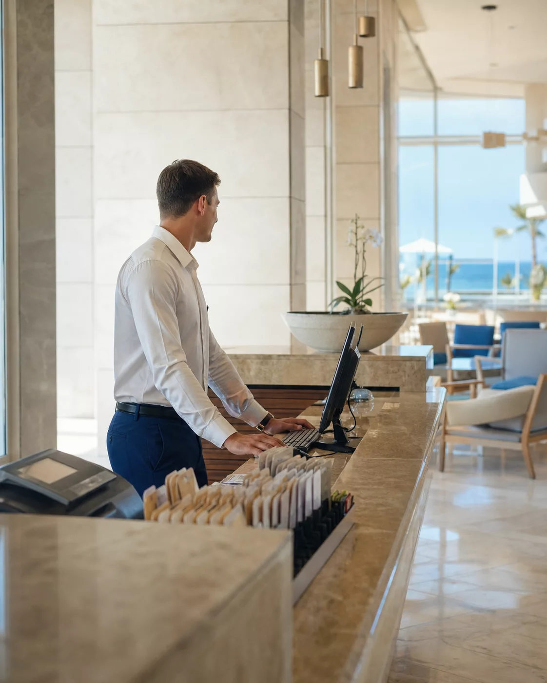 Hotel receptionist working at a bright seaside front desk
